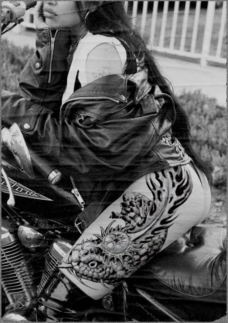 Diseño de María Vera mostrado en mockup sobre una fotografía de archivo en blanco y negro: mujer con cazadora de cuero tumbada sobre una moto, con una composición ornamental de llamas y filigrana en el muslo.