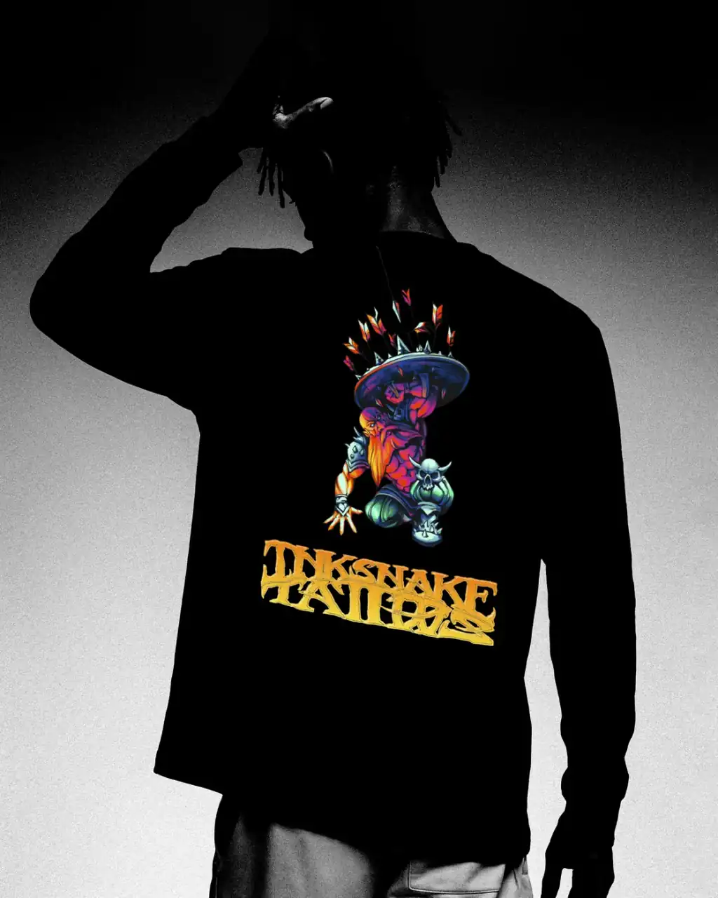 Camiseta negra de manga larga de InkSnake vista por la espalda, con una criatura a color y el rótulo InkSnake Tattoos en dorado.